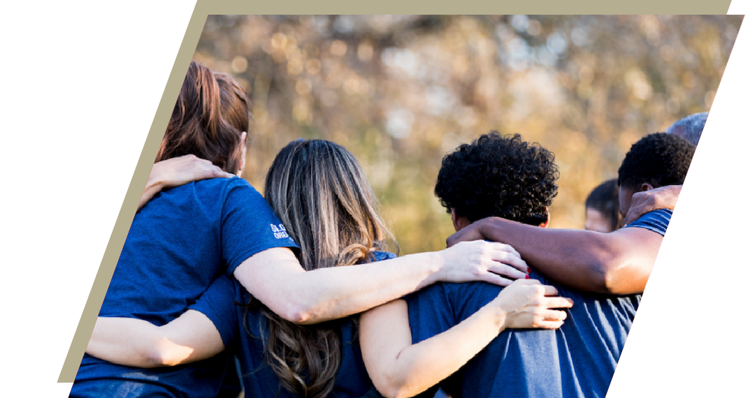 Group of students with their backs to the camera and arms around each others shoulders.