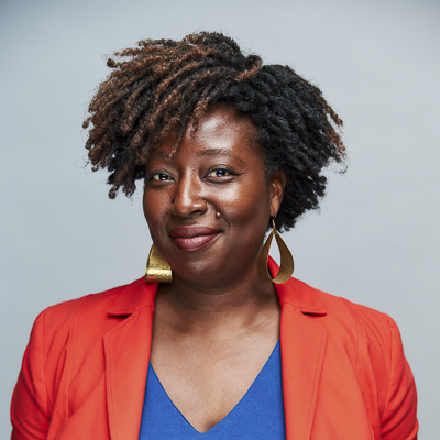 afua bruce a person with dark hair and a red blazer and a blue shirt